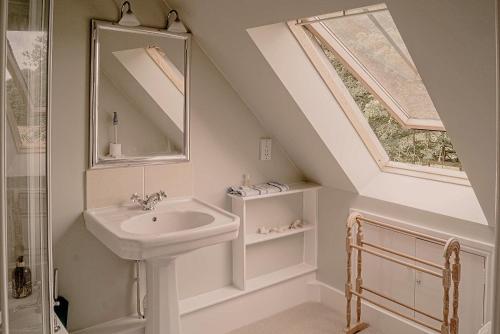 a white bathroom with a sink and a window at The Old Dairy (Chute Forest) in Andover