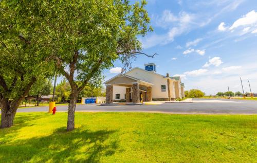 a building on a street with a tree in the grass at Cobblestone Inn & Suites - Winters in Winters
