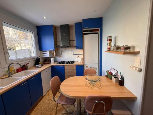 une cuisine avec des placards bleus et une table en bois dans l'établissement Le Coquelicot - Centre - 8 Pers - Parking, au Mans