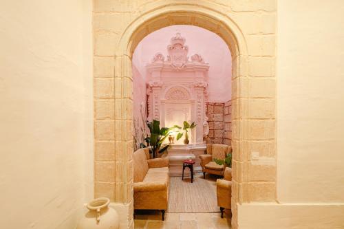 森格莱阿Senglea Jungle Palazzo的一座拱门,位于一座配有沙发和椅子的建筑中