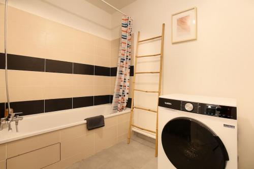 La salle de bains est pourvue d'un lave-linge et d'une baignoire. dans l'établissement NEW-Le Patio St Cyprien - Parking - Terrasse - Netflix, à Toulouse