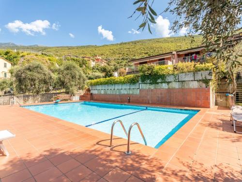 a swimming pool in a villa with a hill in the background at GuestHost - Lake Garda Lovely Flat with Pool in Assenza di Brenzone
