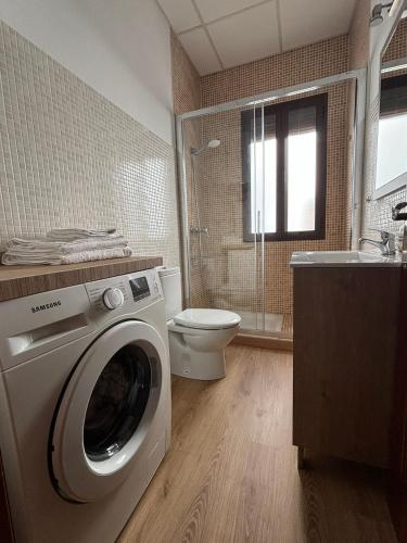 a bathroom with a washing machine and a toilet at Casa Yaye Puerta Palma - Écija in Écija