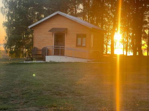 a small house in a yard with the sun setting at Rāznas ezera namiņš D1 ar elektrisko apkuri in Ragi