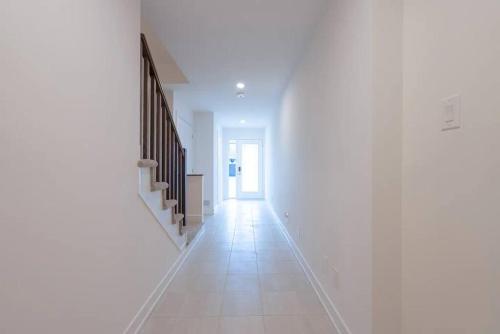 a hallway with white walls and a white tile floor at 2 Bedroom Modern Home & Close to Airport Downtown in Ottawa