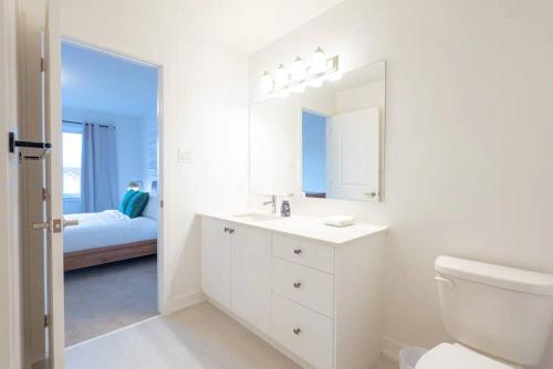 a white bathroom with a toilet and a mirror at 2 Bedroom Modern Home & Close to Airport Downtown in Ottawa