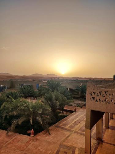 a sunset over the desert with a sign in the foreground at Sahara Sands Hotel in Merzouga