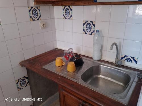 a kitchen sink with two yellow mugs on it at Maison la rose 2 chambres in Mezraya