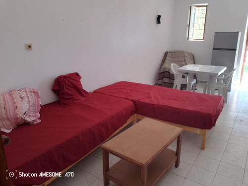 a bedroom with a red bed and a table and a chair at Maison la rose 2 chambres in Mezraya