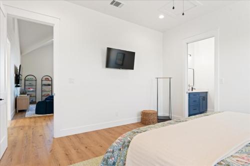 a white bedroom with a bed and a tv on a wall at New Lake Retreat Sleep 17 Poolspagameroomview in Granite Shoals