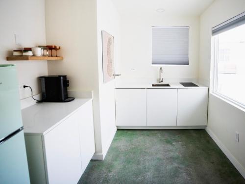 a kitchen with white cabinets and a sink at The Cactai in Palm Springs