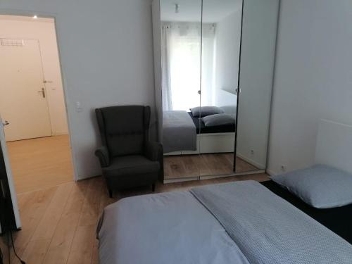 une chambre avec un lit, une chaise et un miroir dans l'établissement AGON Lodge, à Rosny-sous-Bois