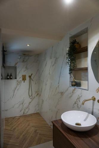 La salle de bains est pourvue d'un lavabo et d'un mur en marbre. dans l'établissement Appartement RDC en Bas de Villa avec Chambre, à Le Val