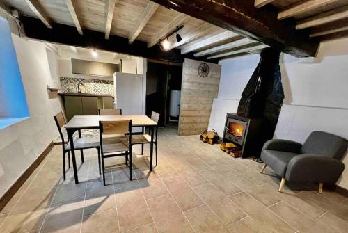Gîte la petite maison في Soulan: غرفة طعام مع طاولة وكراسي ومدفأة