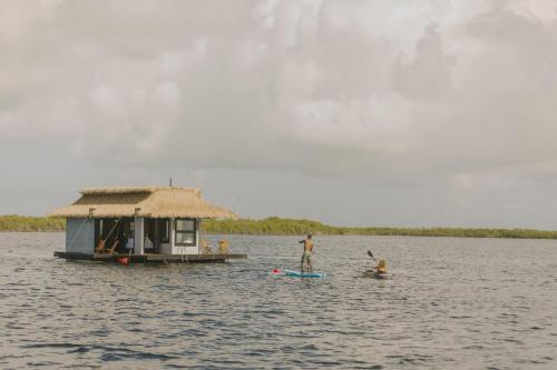 two people on paddle boards in the water with a hut at Premium Floating Bungalow by Stay Ombi in Key Largo