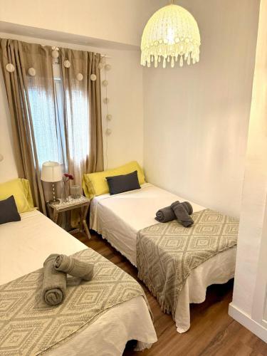 a bedroom with two beds and a chandelier at Apartamento con Parking El Rincón del Arte Granada Centro in Granada