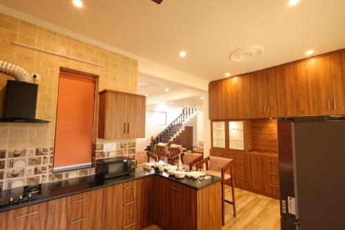 a kitchen with wooden cabinets and a black refrigerator at Vista Valley Stay, Luxury 3 BHK Villa Kangra, Dharamshala in Dharamshala
