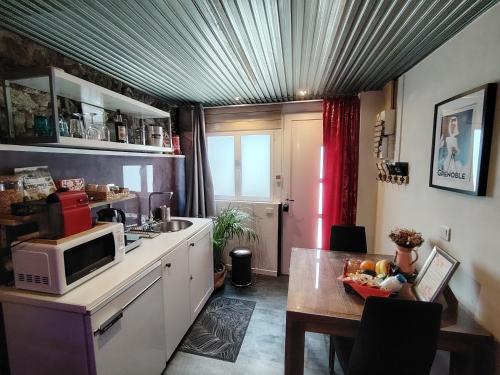 - une cuisine avec une table et un four micro-ondes dans l'établissement Sweet Loft Grenoble-Love Room avec jacuzzi & sauna, à Grenoble