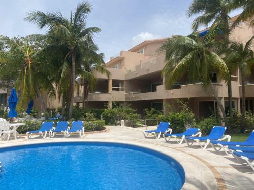 a resort with a pool and chairs and palm trees at Rent Portobello Marina y Villas in Puerto Aventuras