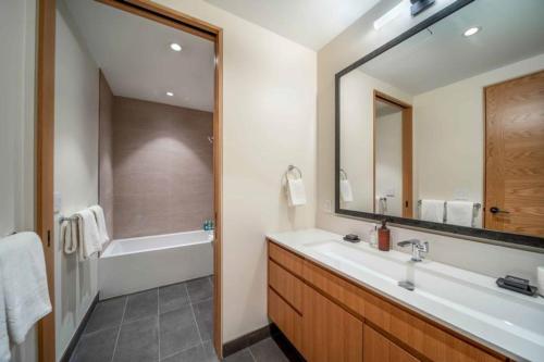 a bathroom with a tub and a sink and a mirror at One Snowmass West 501 by Snowmass Mountain Lodging in Snowmass