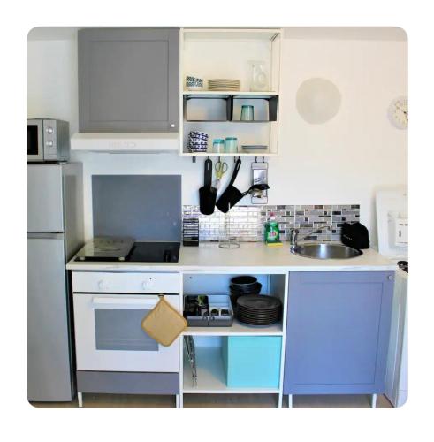 Elle comprend une petite cuisine avec des placards bleus et blancs et un évier. dans l'établissement Studio 18, au Havre