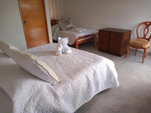 a teddy bear sitting on top of a bed at Feliz Amanecer in Sáchica
