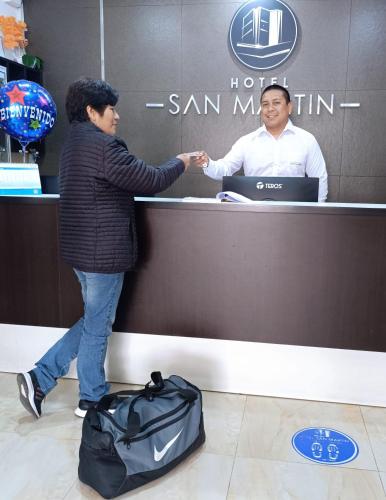 a woman shaking hands with a man at a counter at Hotel San Martín in San Juan de Marcona