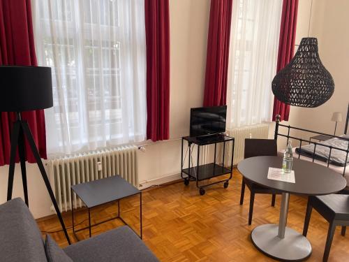 a living room with a table and red curtains at WHLIVING - Apartments & Studios in Konstanz in Konstanz