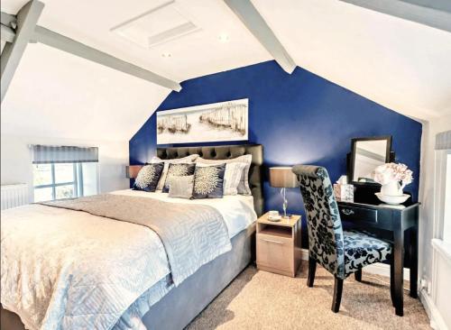 a bedroom with a blue wall with a bed and a desk at Charming Shepherd's Cottage, Pets Welcome,parking in Bridgend