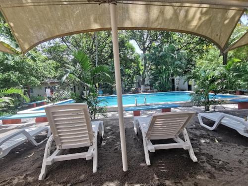 two chairs and an umbrella next to a swimming pool at Rincon del mar in La Libertad