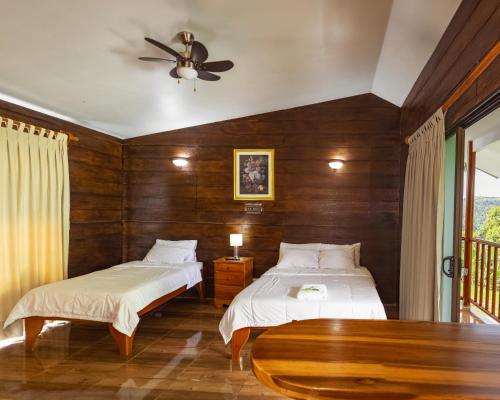 Un dormitorio con dos camas y una pared de madera. en Cabañas Bambú, en San Vito
