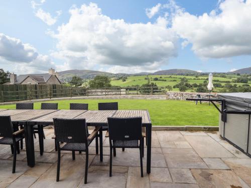 a table and chairs on a patio with a view of a field at Bwthyn Y Bugail Shepherd's Cottage in Oswestry