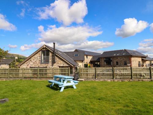 a blue picnic table in the grass in front of a house at Y Stabl The Stable in Oswestry