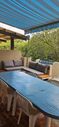 une table bleue assise sur une terrasse avec un canapé dans l'établissement Au BleuRivage, à Ensuès-la-Redonne