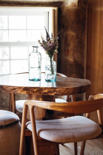 a wooden table with a glass bottle and flowers on it at Story Studio Sortelha - Heritage in Sortelha