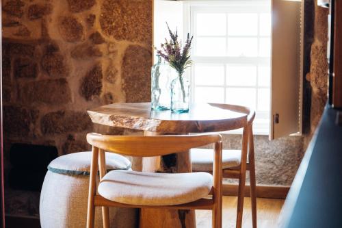 a table with two chairs and a vase with flowers on it at Story Studio Sortelha - Heritage in Sortelha