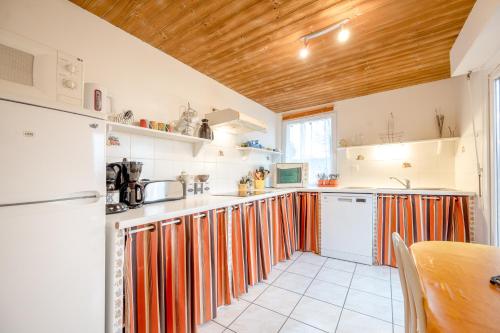 une cuisine avec des placards à rayures orange et blanc et une table dans l'établissement Les Clématites, à Hillion