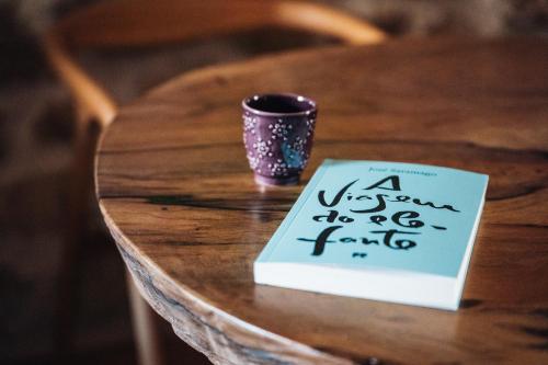 a coffee cup sitting on a wooden table with a sign at Story Studio Sortelha - Heritage in Sortelha