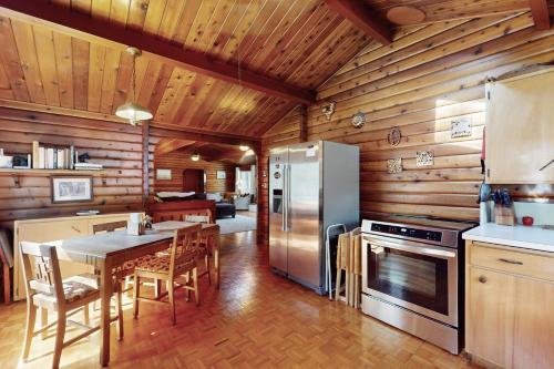 a kitchen with a table and a refrigerator at Log Cabin on the River in Hawkins Bar