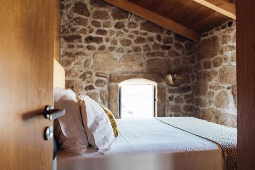 a bed in a room with a stone wall at Story Studio Sortelha - Heritage in Sortelha