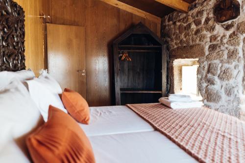 a bedroom with a bed and a stone wall at Story Studio Sortelha - Heritage in Sortelha