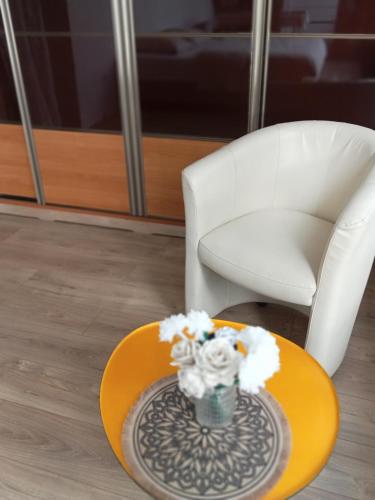 a white chair and a table with a vase of flowers at Grand studio tout équipé in Ploërmel