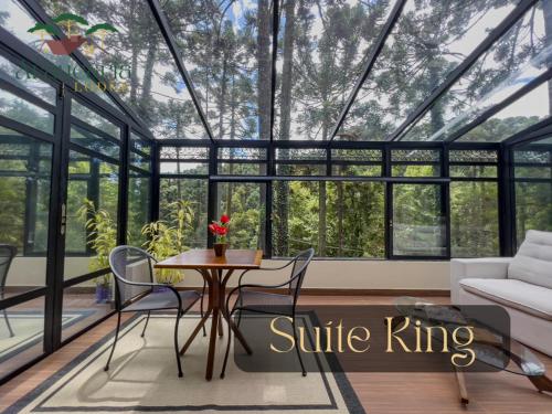 a glass house with a table and chairs in a living room at Araucária Lodge - 800 metros do Capivari in Campos do Jordão