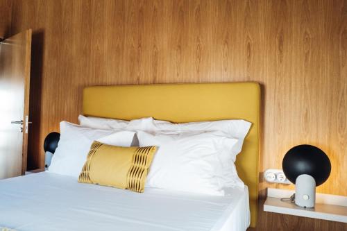 a bed with a yellow headboard and white pillows at Story Studio Sortelha - Heritage in Sortelha