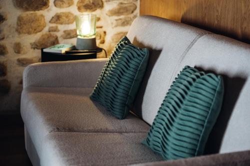 a couch with two pillows on a table with a lamp at Story Studio Sortelha - Heritage in Sortelha