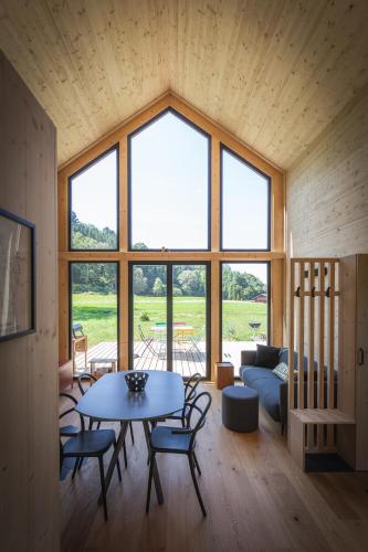 une pièce avec une table et des chaises et une grande fenêtre dans l'établissement La Cabane des Prés, à Ban-sur-Meurthe-Clefcy