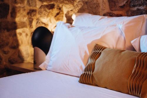 a bed with white sheets and pillows in a room at Story Studio Sortelha - Heritage in Sortelha