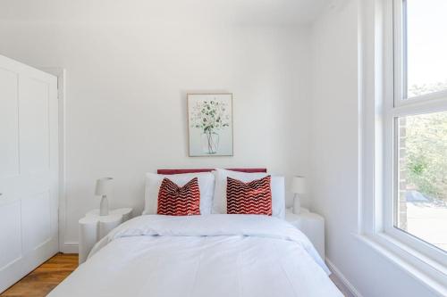a white bedroom with a bed with red pillows at Urban Oasis 4 bedroom house with parking in Chatham