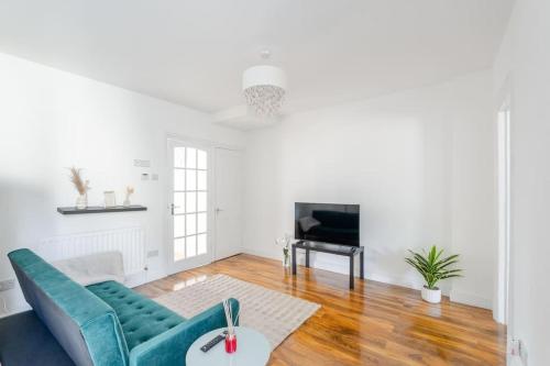 a living room with a blue couch and a television at Urban Oasis 4 bedroom house with parking in Chatham