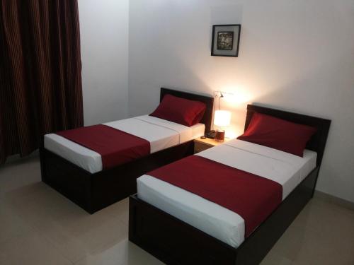 two beds in a hotel room with red and white sheets at Azaiba Hotel Apartments in Muscat